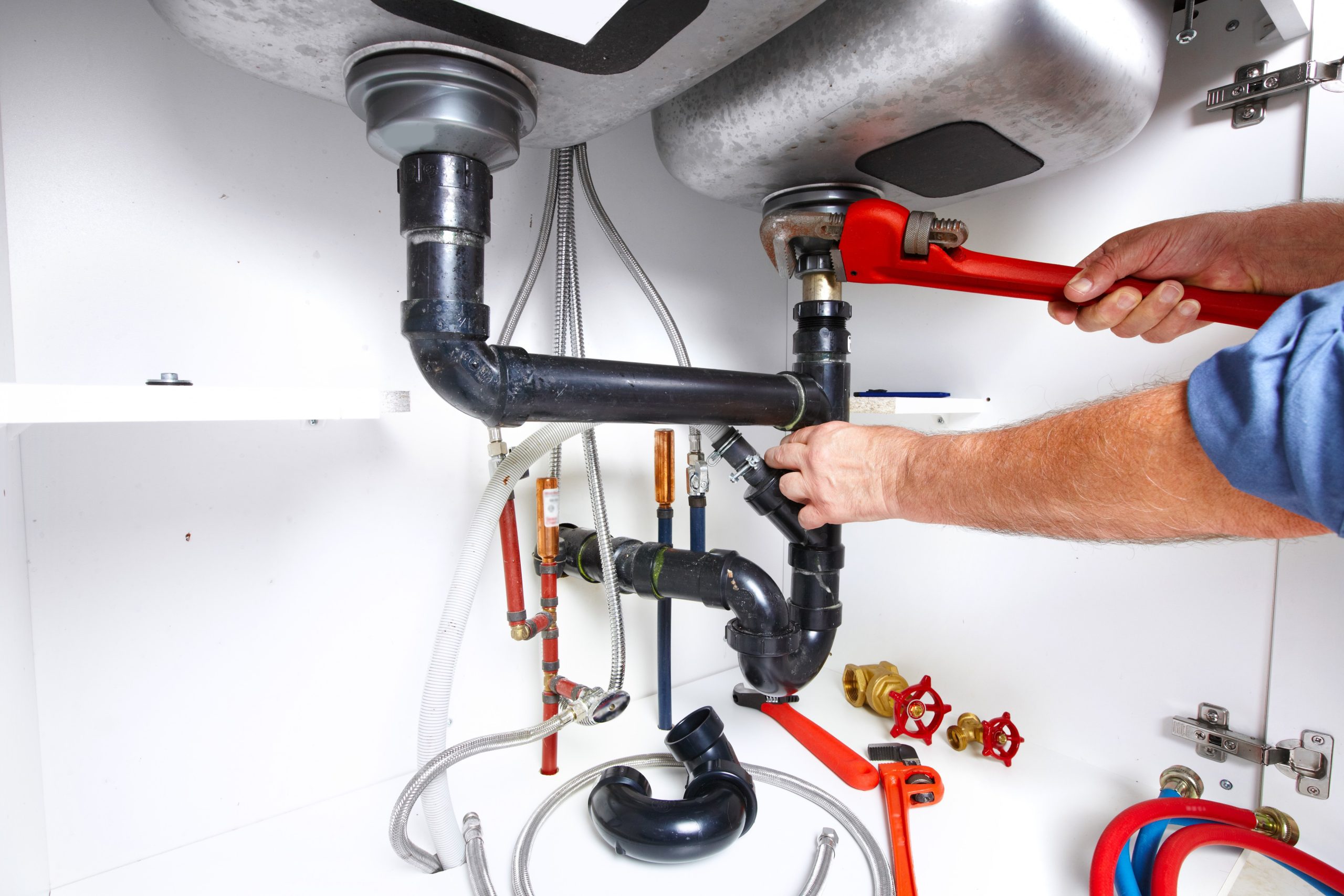 Close-up of the hands of a plumber, fixing pipes under a sink.